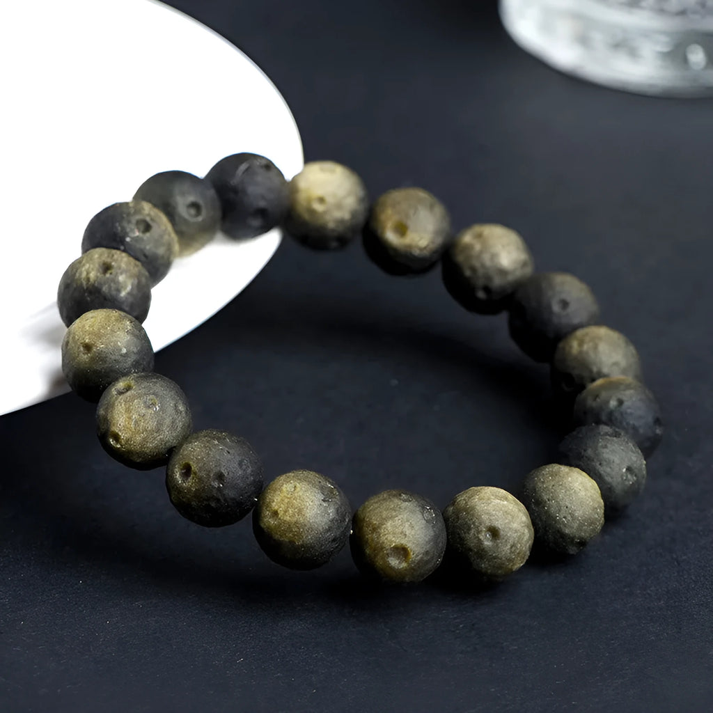Natural obsidian crater ball bracelet in gold or silver meteorite finish on a wrist.