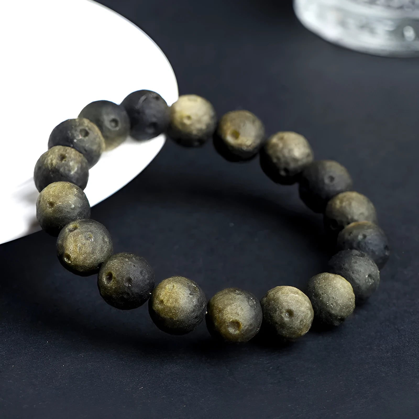 Natural obsidian crater ball bracelet in gold or silver meteorite finish on a wrist.