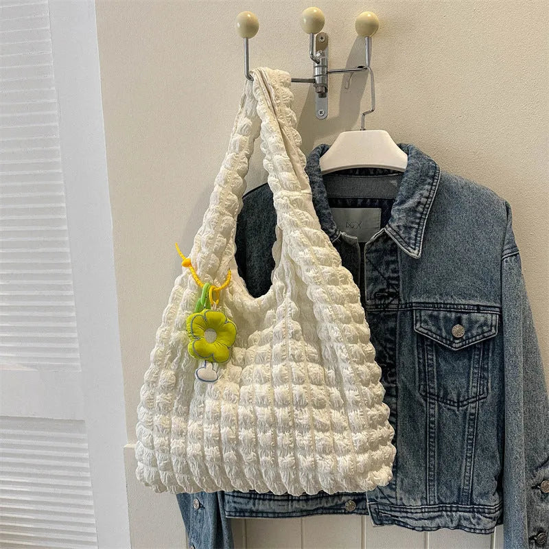 Pleated bubble bag in beige polyester with fold detailing, pendant, and cross-body strap