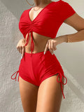Women's dark green lace-up bow swimsuit top with matching shorts laid flat.