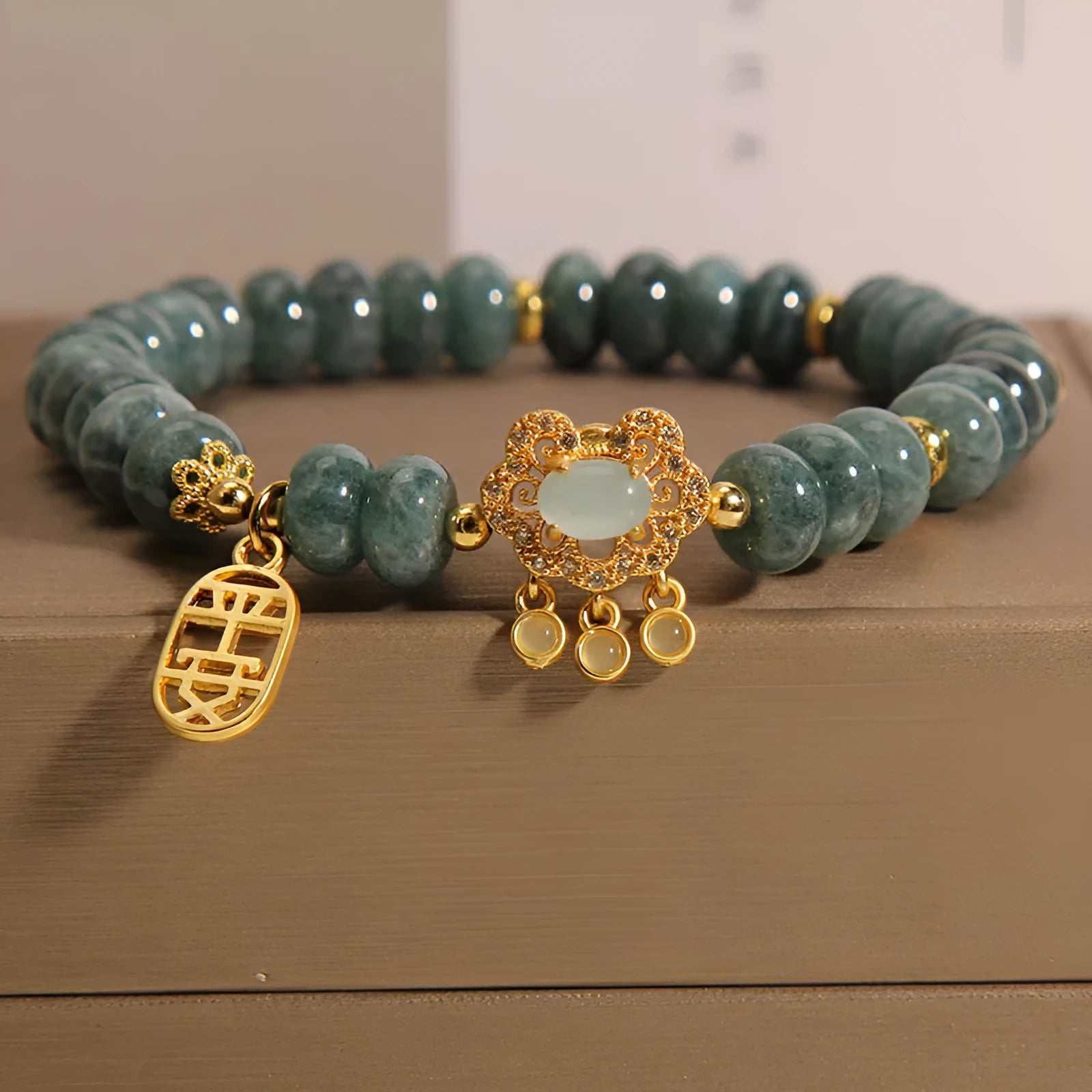 Close-up of a women's bracelet with green emerald jade abacus beads and a metallic alloy safety lock clasp.