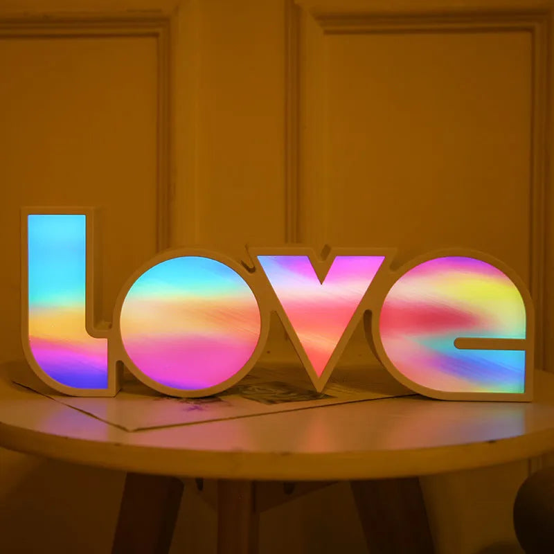 LED LOVE light with rainbow lampshade on a table against a dark background