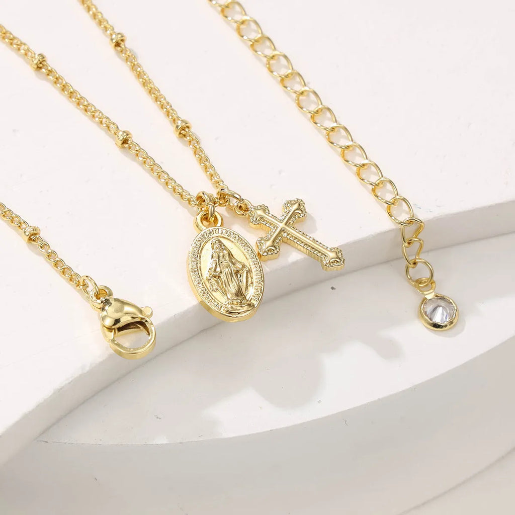 Gold geometric cross necklace with Virgin Mary ornament on a simple chain.
