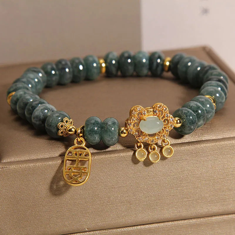 Close-up of a women's bracelet with green emerald jade abacus beads and a metallic alloy safety lock clasp.