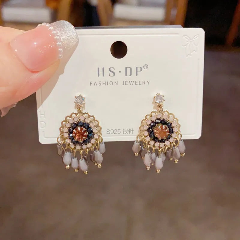 Pair of diamond embedded round crystal tassel earrings, thick gold plated, purple colour, on a white background