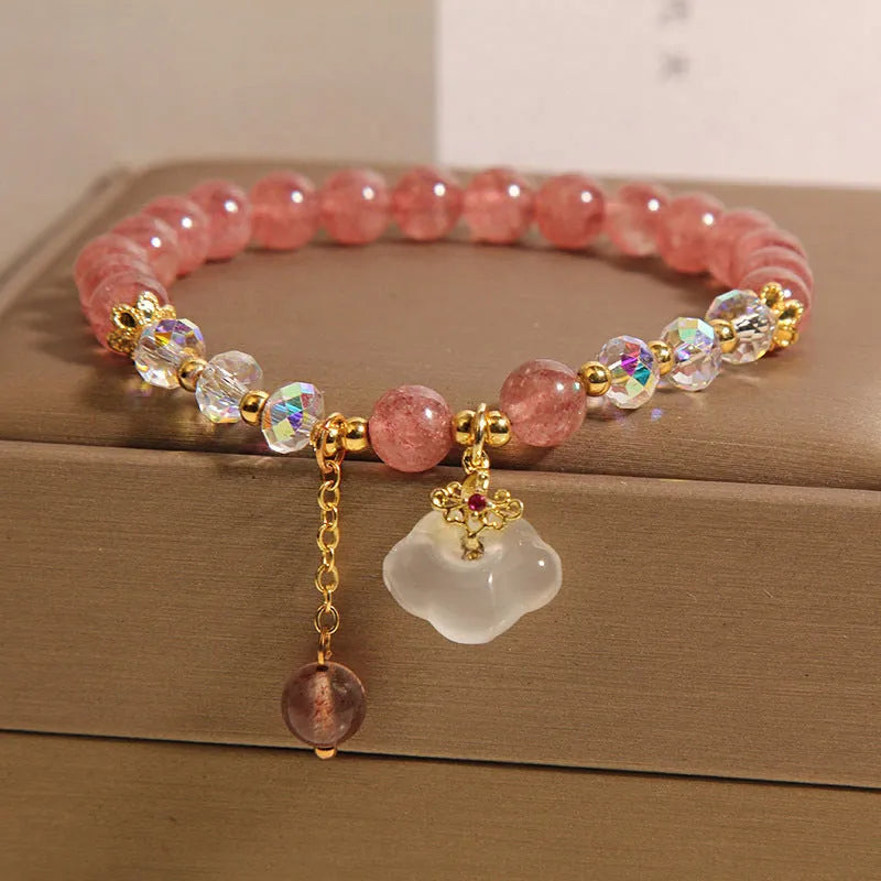 Women's natural strawberry quartz and white agate crystal bracelet with auspicious cloud pattern on a flat surface