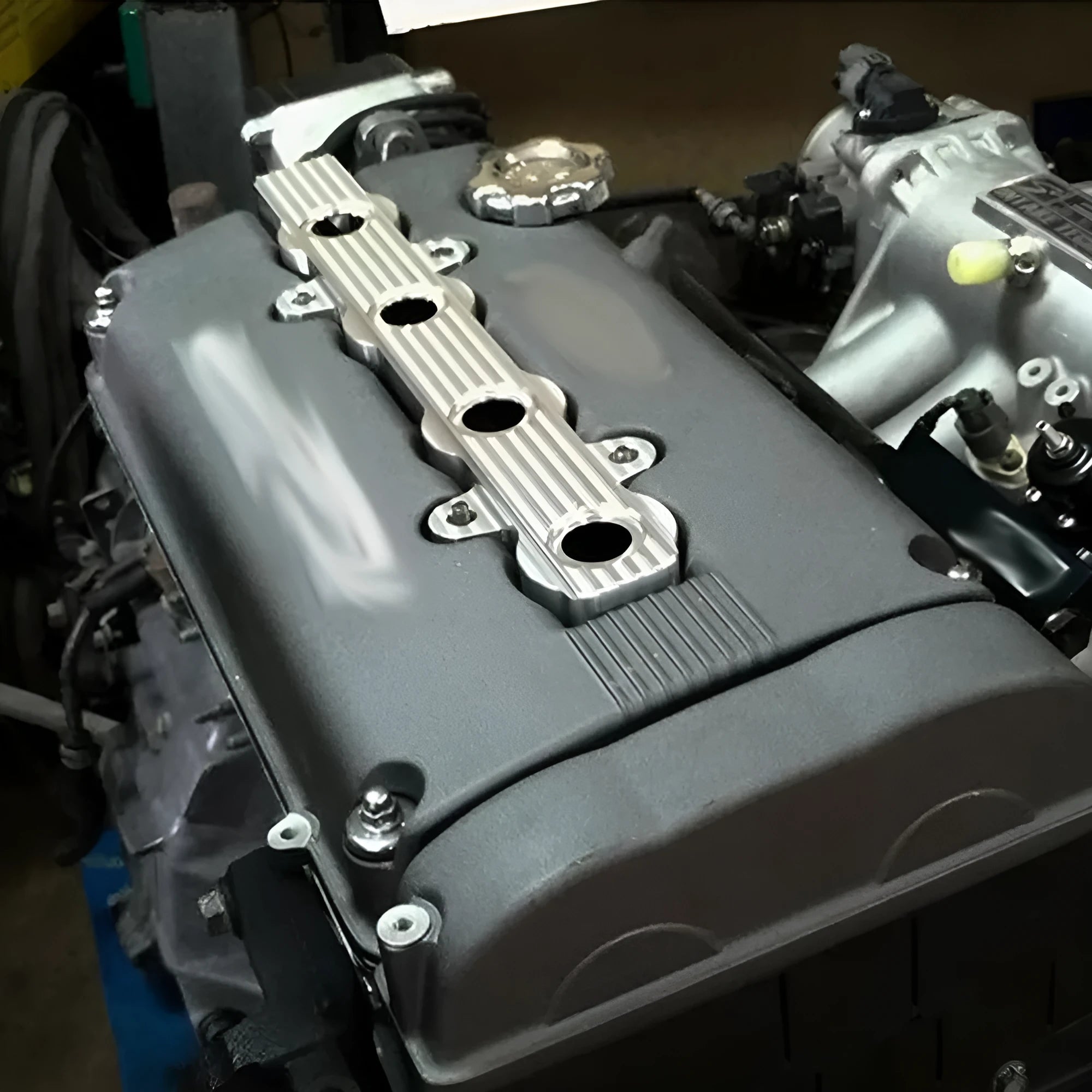 Aluminium alloy engine harness mounting bracket in blue, red, or silver finish, shown with and without pre-drilled holes.