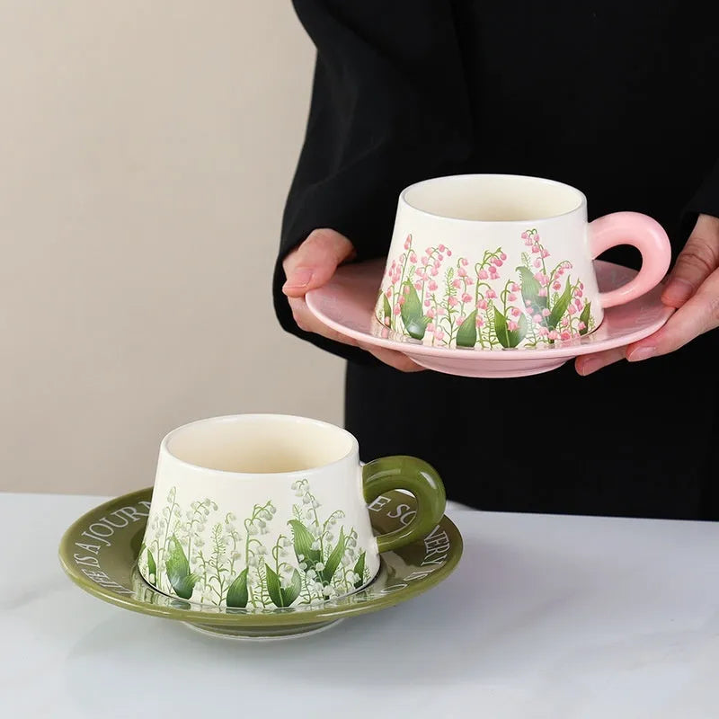 Ceramic coffee cup saucer set with two cups, two plates, and two spoons in matching design