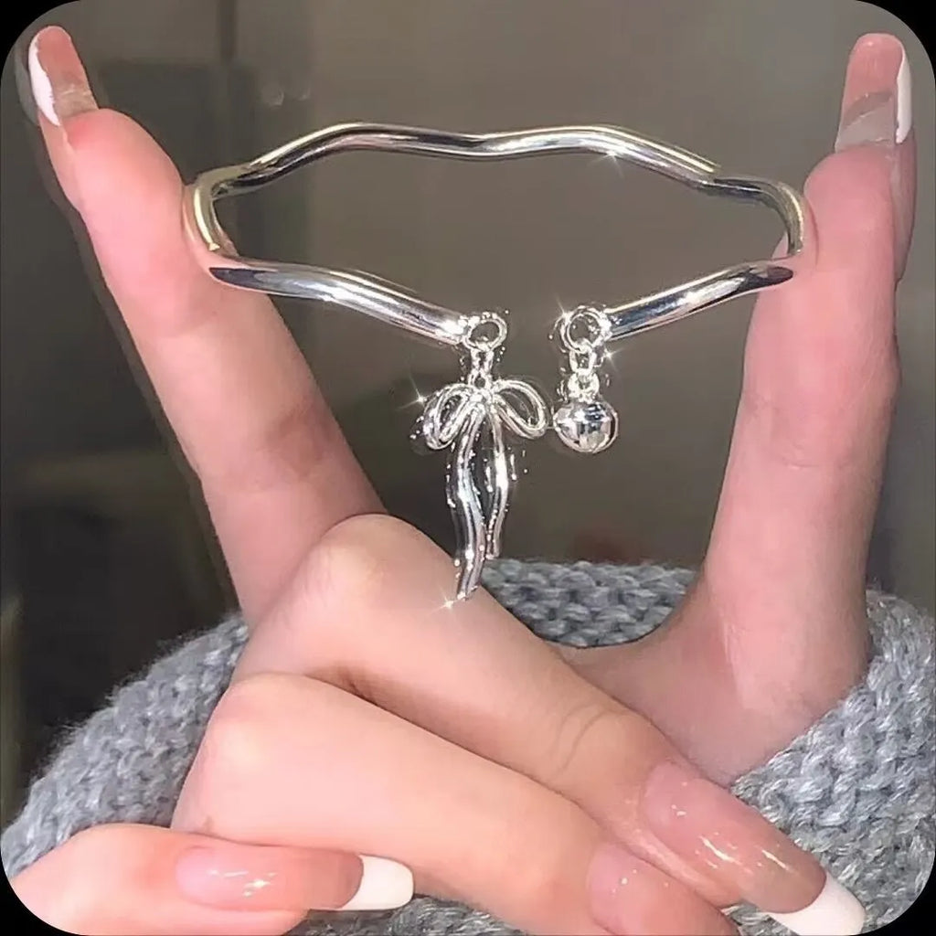 Silver adjustable bracelet with bow charm and small bell detail on wrist