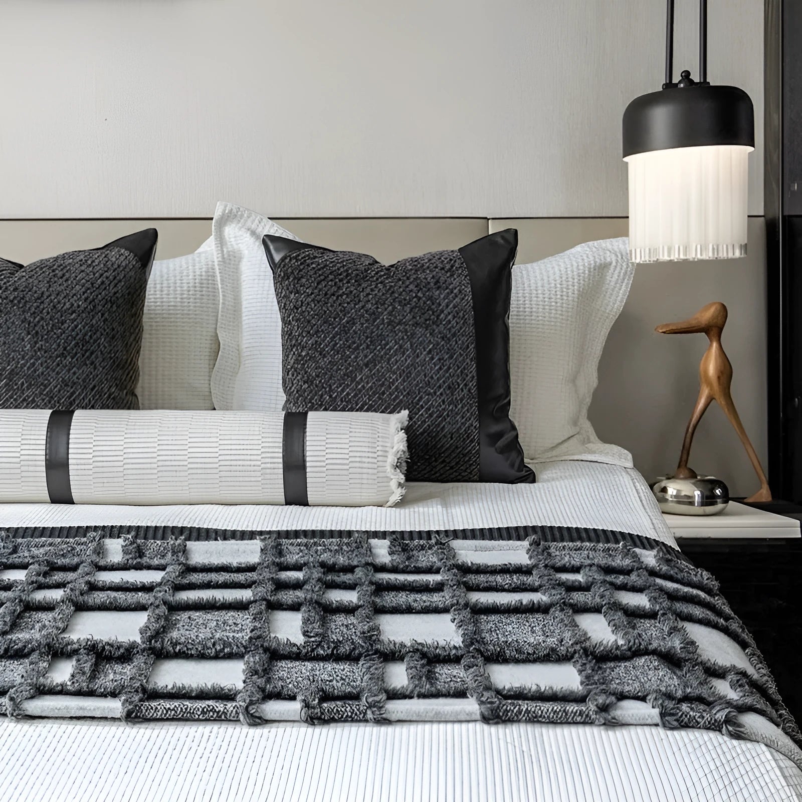 Grey and white plaid bed runner blanket with leather round pillow on bed