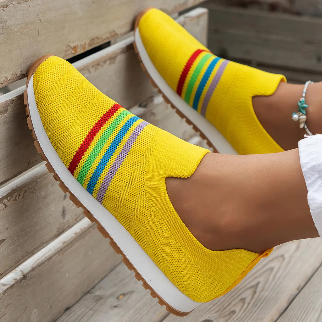 Women's casual flat sneaker pumps in beige with low wedge heel and round toe, side view on wooden floor