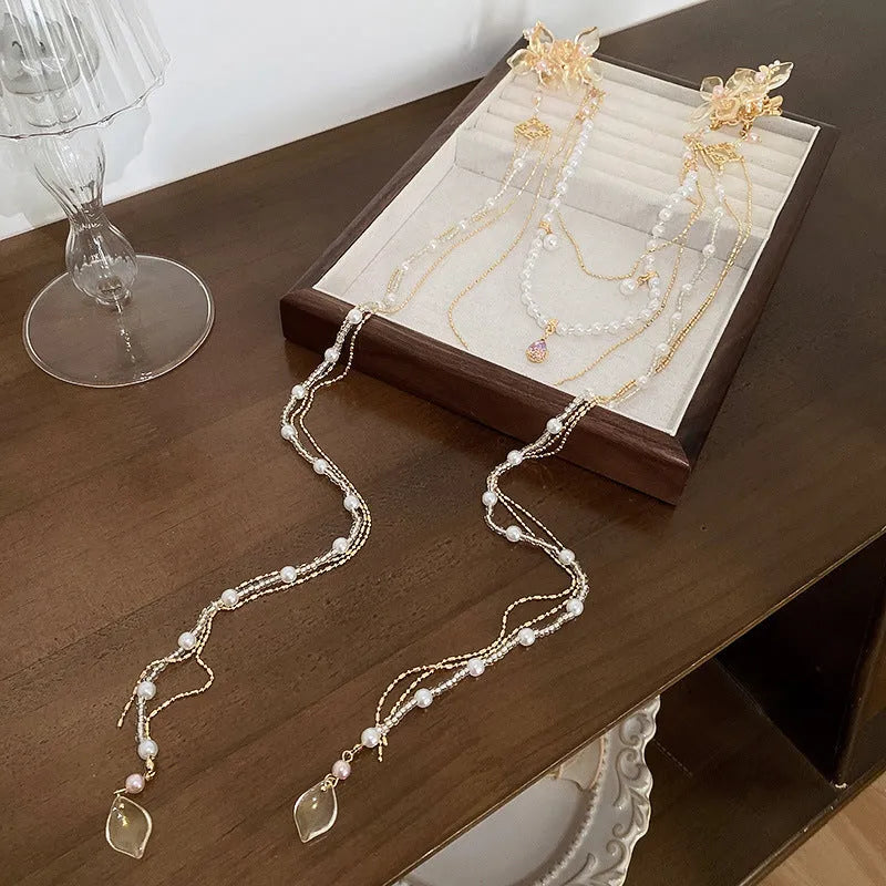 Gold acrylic hairpin with a pearl and diamond flower decoration and a long tassel.