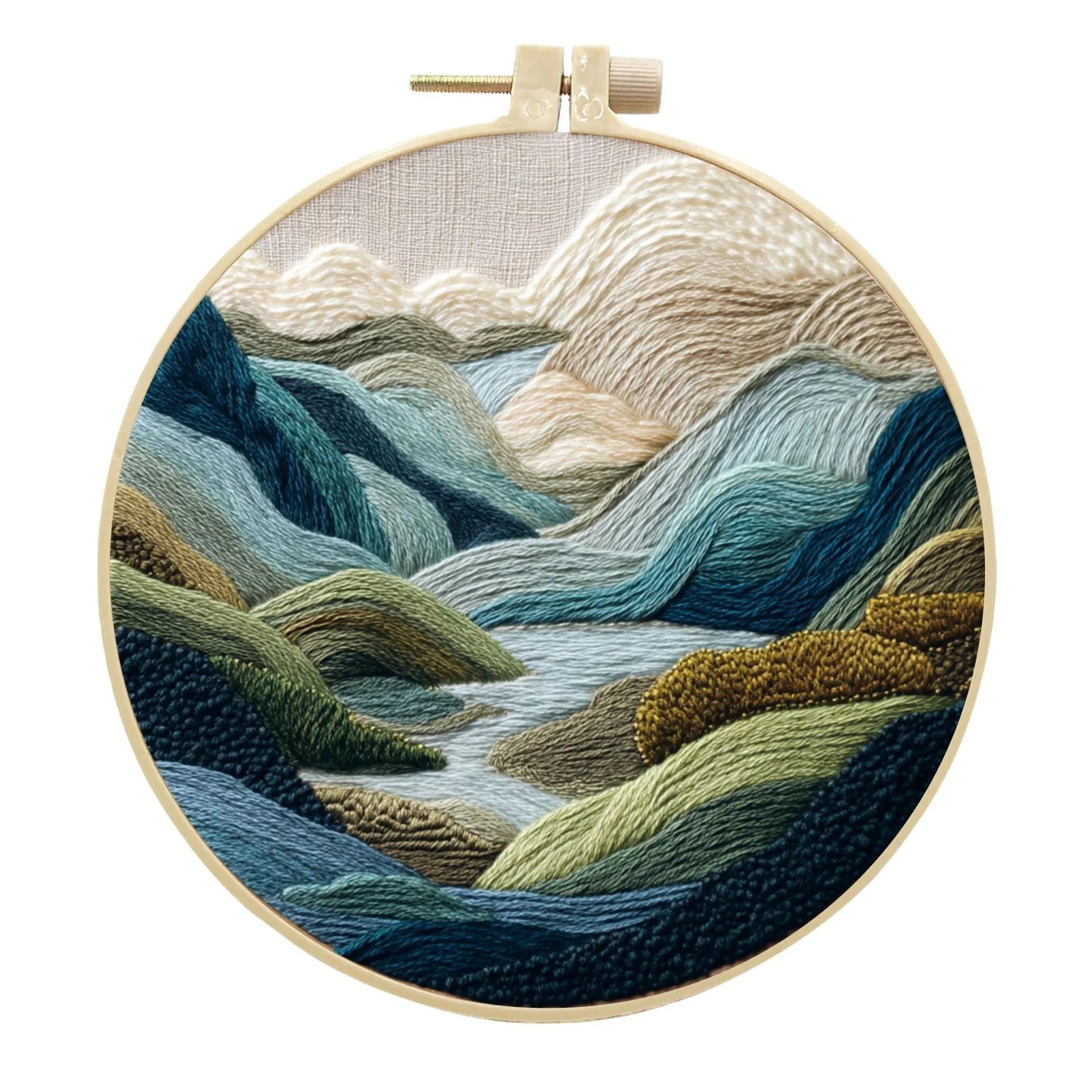 Embroidery DIY kit with cotton landscape fabric, bamboo frame, threads, and tools on wooden surface