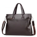 Men's black PU leather crossbody messenger bag with splicing design, shown next to a tablet for scale.