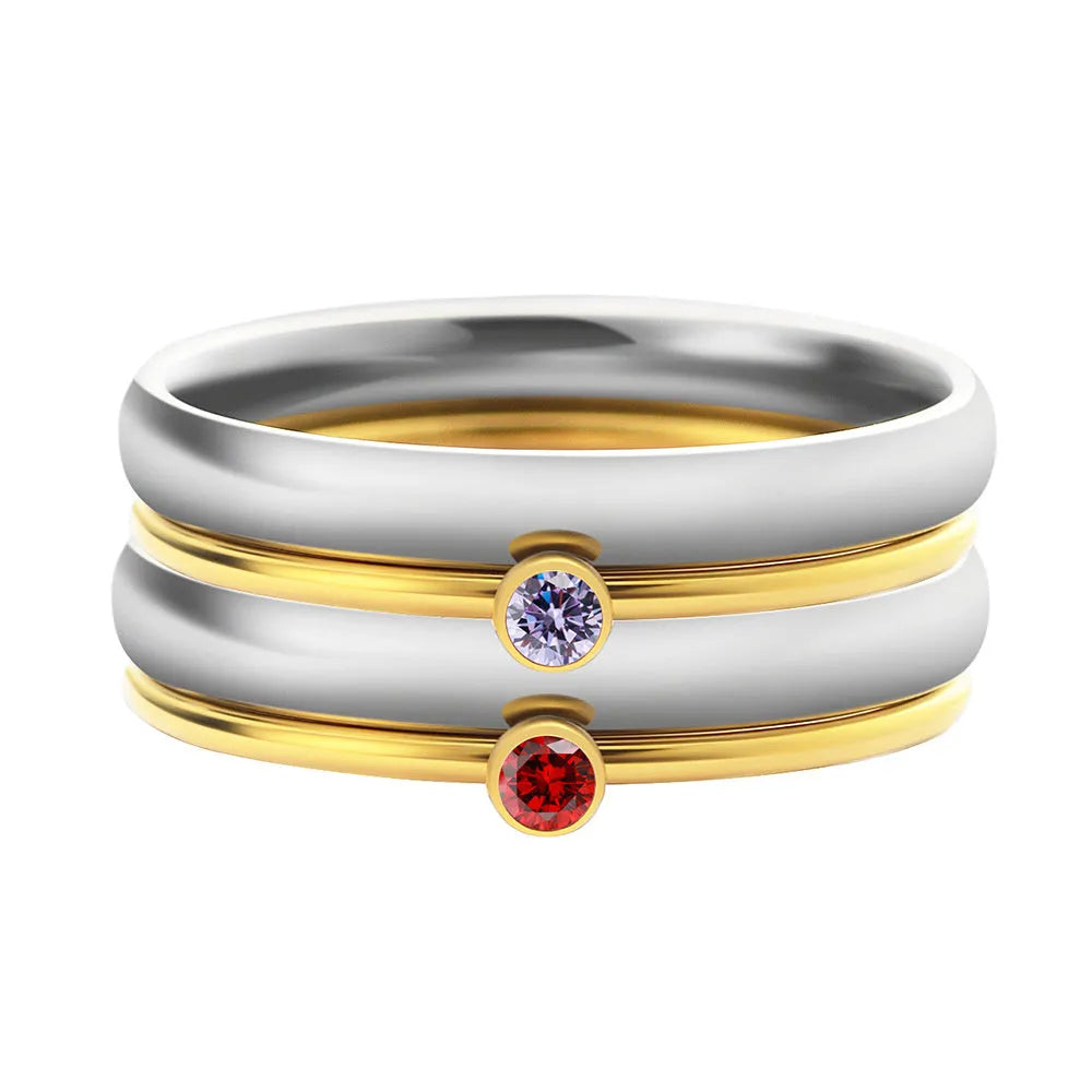 December birthstone ring in titanium steel with geometric engraving and gold accents on a grey background.