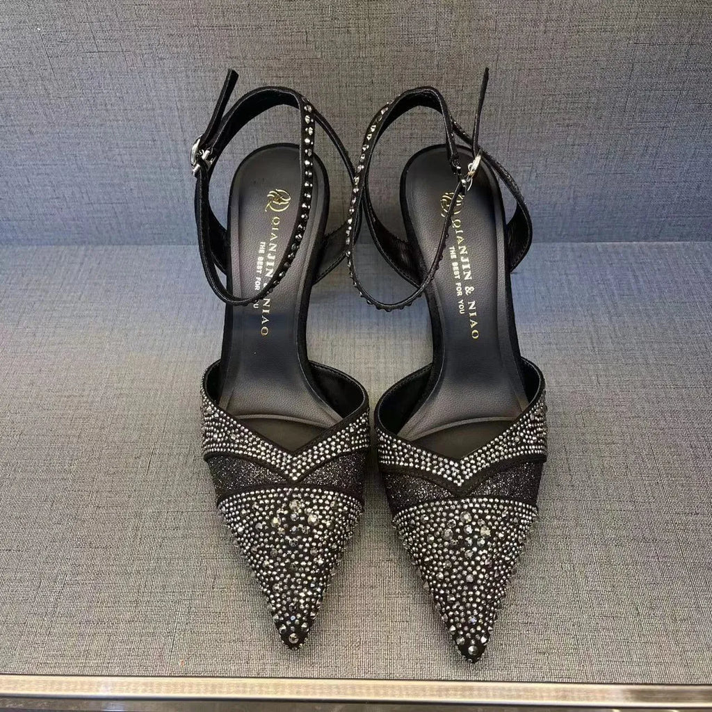 Women's black high heel shoe with pointed toe, stiletto heel, red sole, and hollow design detail.