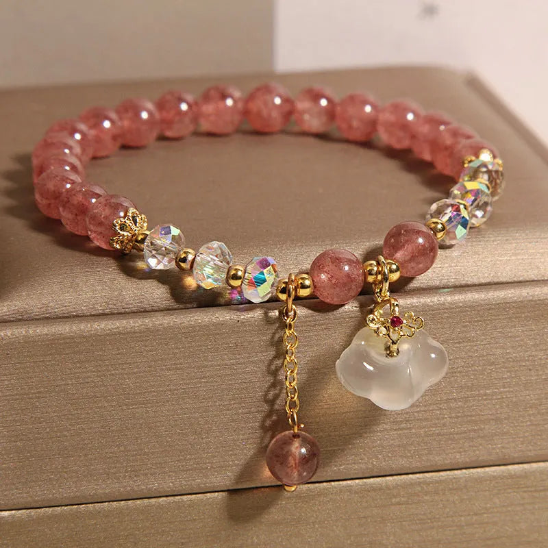 Women's natural strawberry quartz and white agate crystal bracelet with auspicious cloud pattern on a flat surface