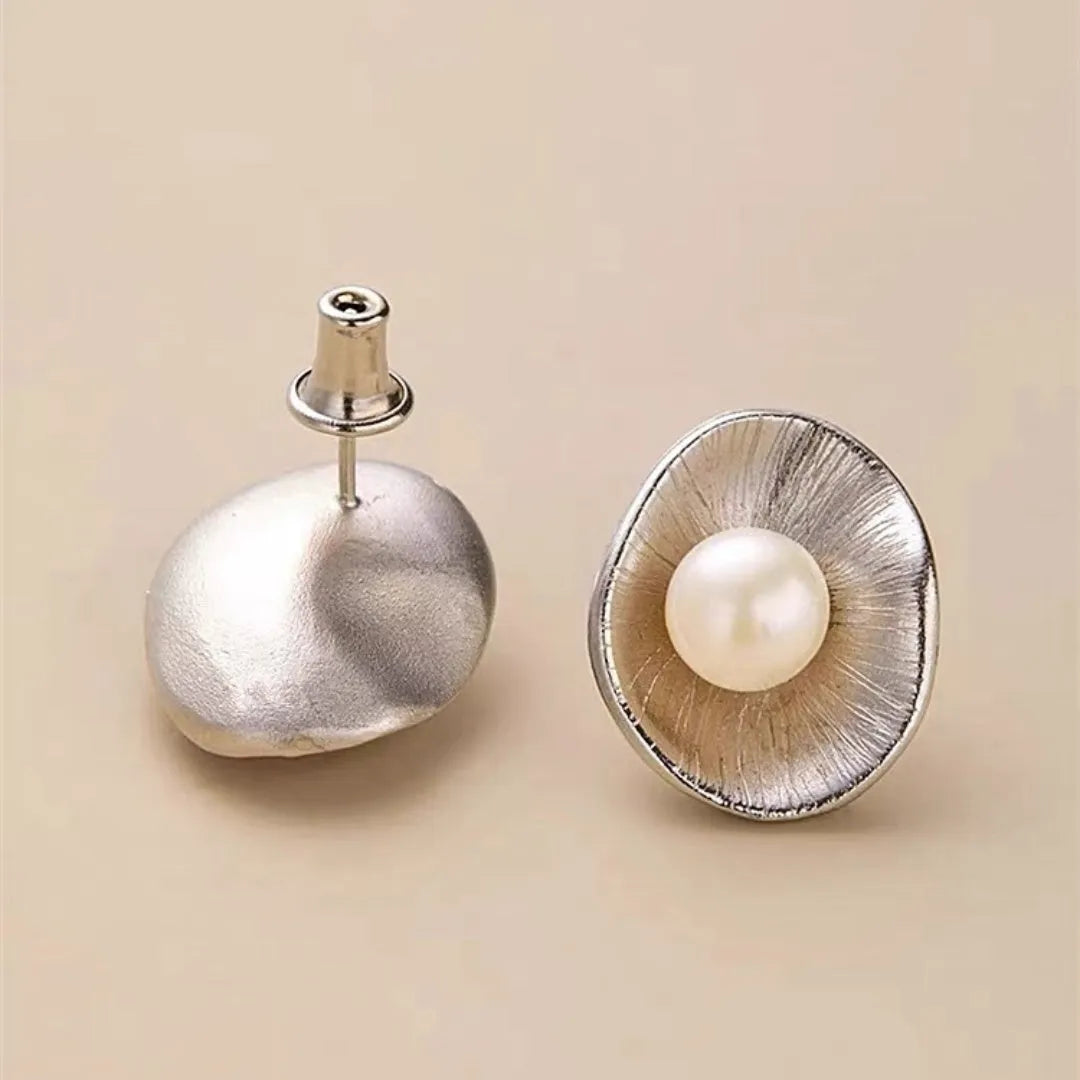 A pair of silver geometric stud earrings with white pearl details on a white background.