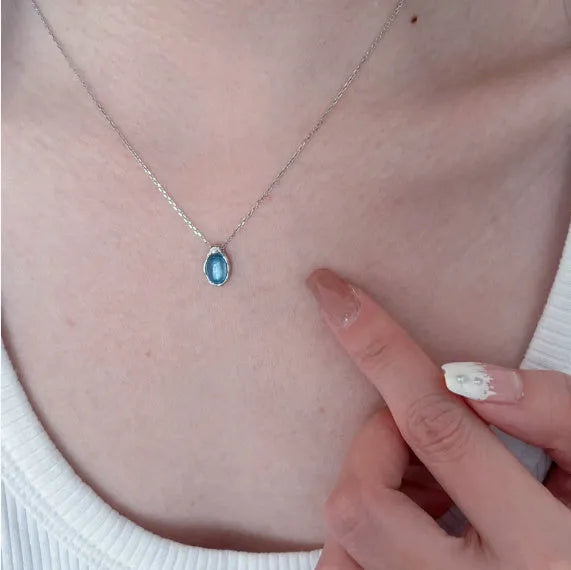 Navy blue water droplet necklace with geometric cross chain on white background