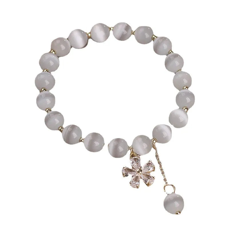 Women's white cat's eye stone bracelet with floral tassel and safety buckle clasp.