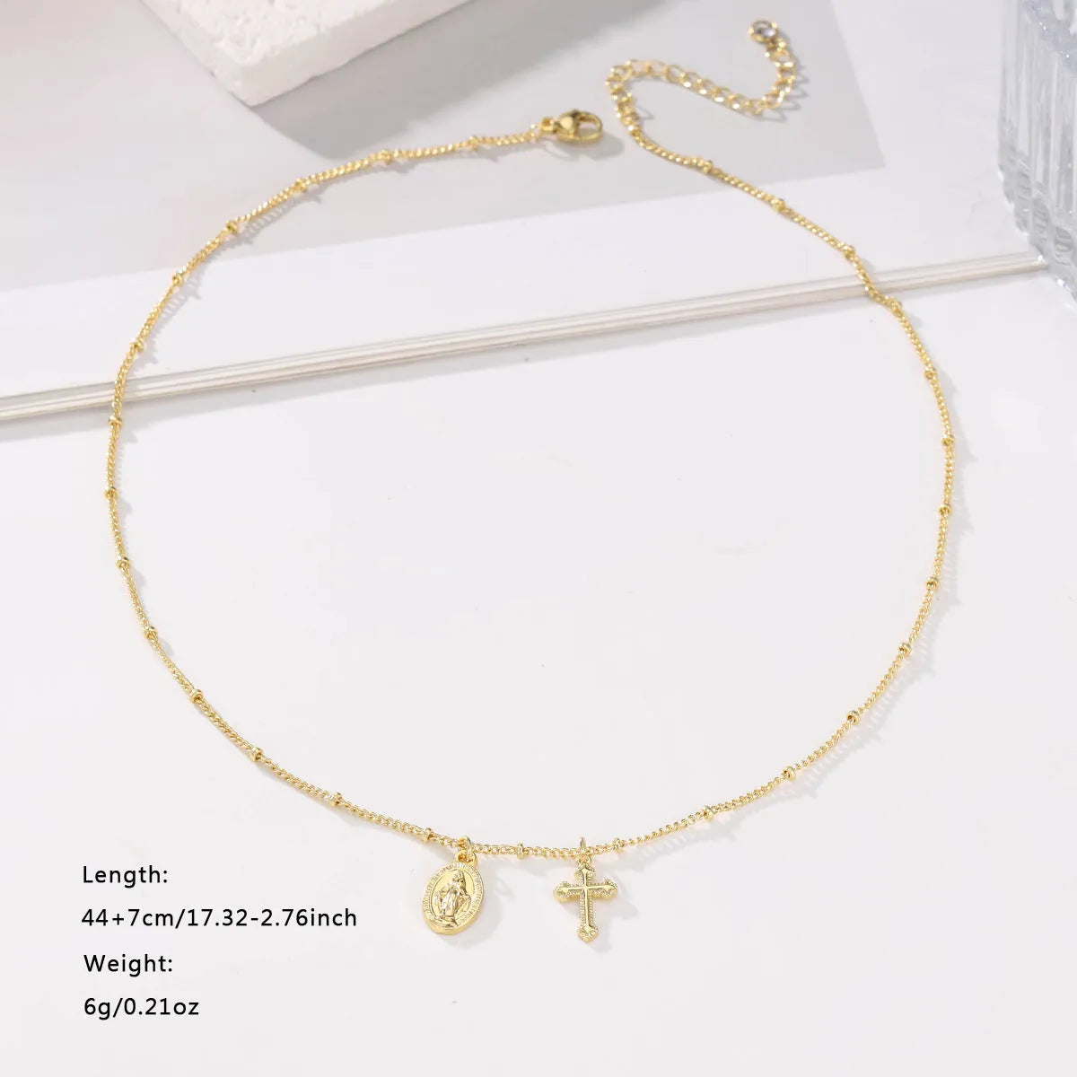 Gold geometric cross necklace with Virgin Mary ornament on a simple chain.