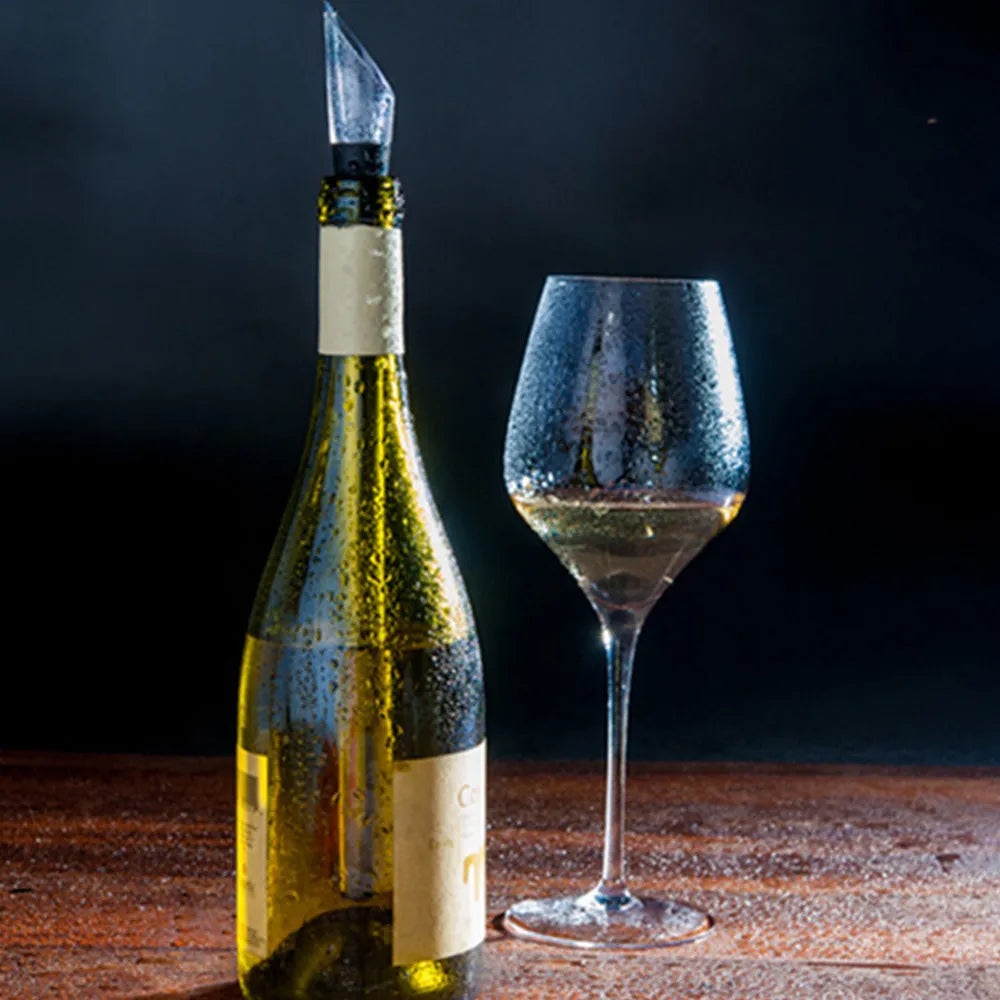 Silver stainless steel wine bottle cooler stick with built-in aerator and drip-free pouring nozzle on a table
