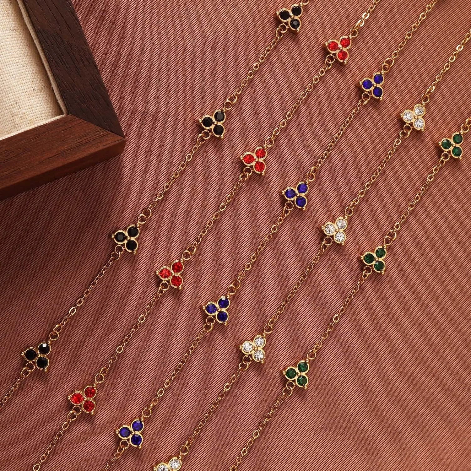 Geometric stainless steel women's bracelet with three diamond shapes and coloured stone settings.