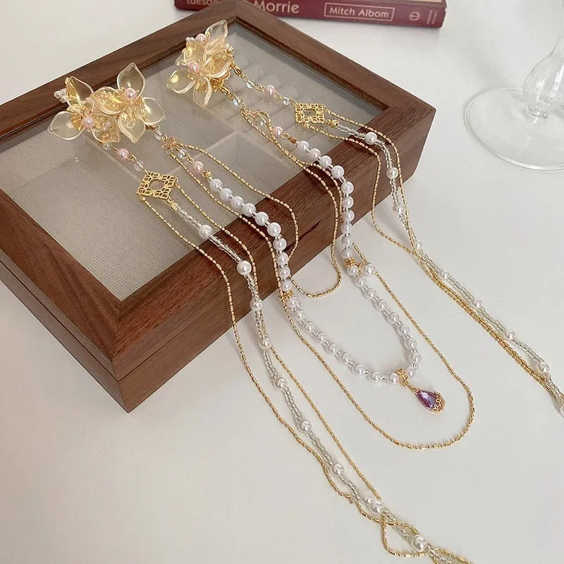 Gold acrylic hairpin with a pearl and diamond flower decoration and a long tassel.