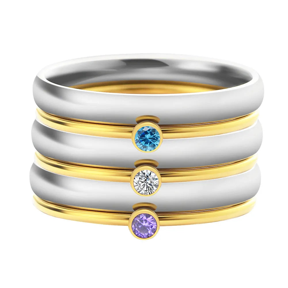 December birthstone ring in titanium steel with geometric engraving and gold accents on a grey background.