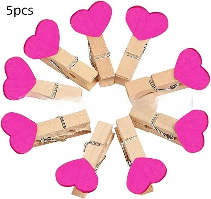 Five wooden heart-shaped clips in different colours on wooden surface