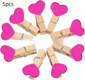 Five wooden heart-shaped clips in different colours on wooden surface