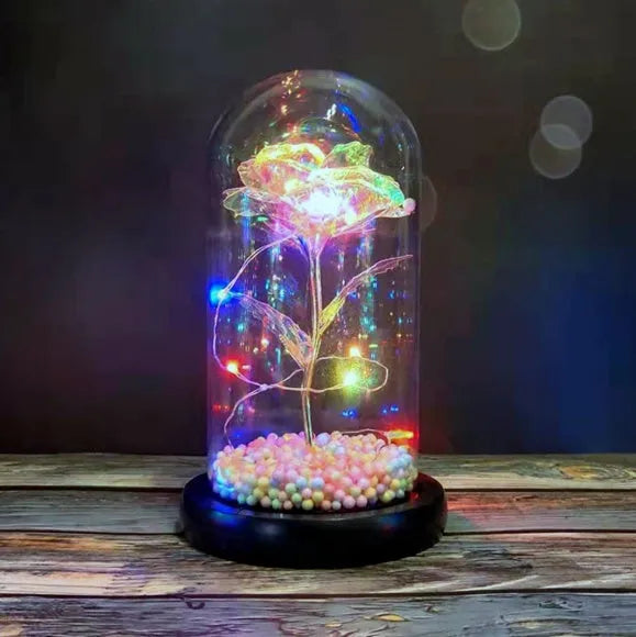 Gold artificial rose inside glass dome with LED lights on black base for home display