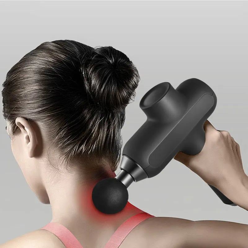 Black rechargeable muscle massager with six different coloured massage heads on a table.
