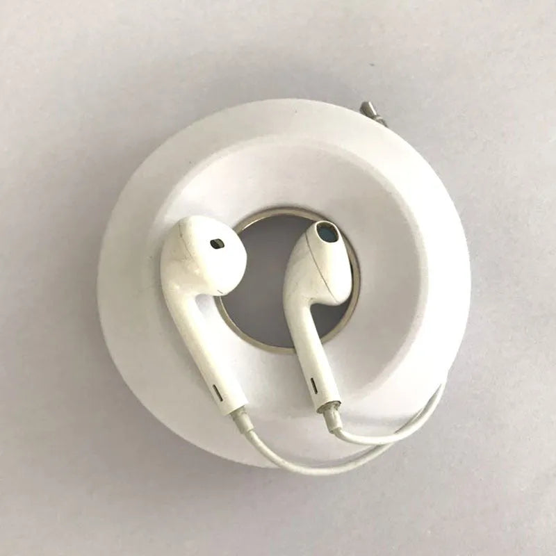 Donut silicone suction cup cord reel in green with earphone cable wound around it and magnet ring closed
