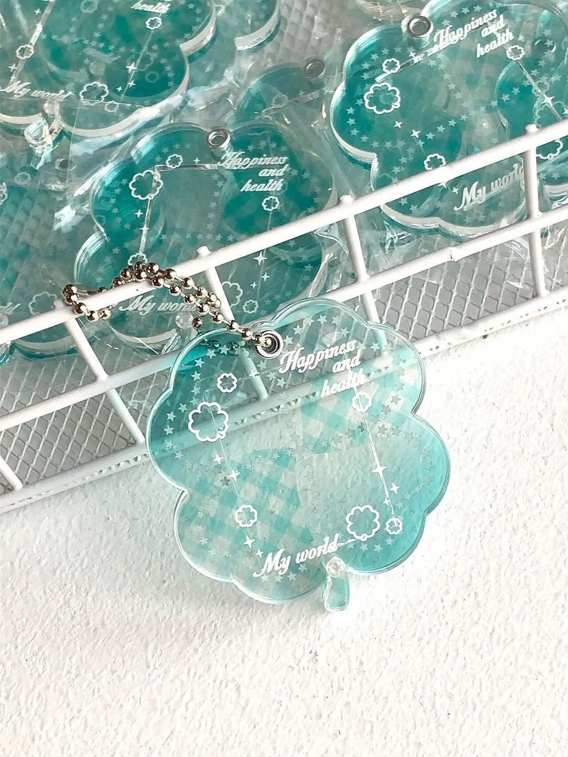 Four-leaf clover shaped acrylic pendant keychain in mint green colour on a surface