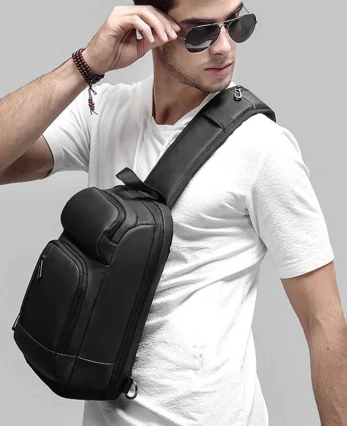 Black PVC outdoor shoulder bag showing computer pocket, air cushion strap, and square vertical design
