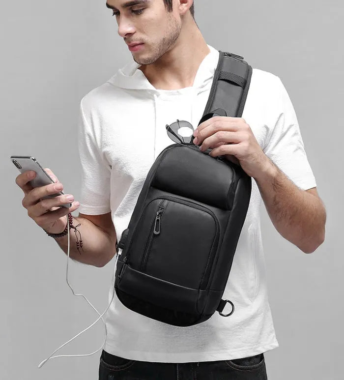 Black PVC outdoor shoulder bag showing computer pocket, air cushion strap, and square vertical design
