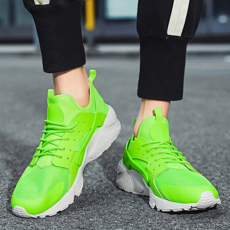 Men's green low top lace-up casual trainers with mesh upper and cross strap detail on a white background.