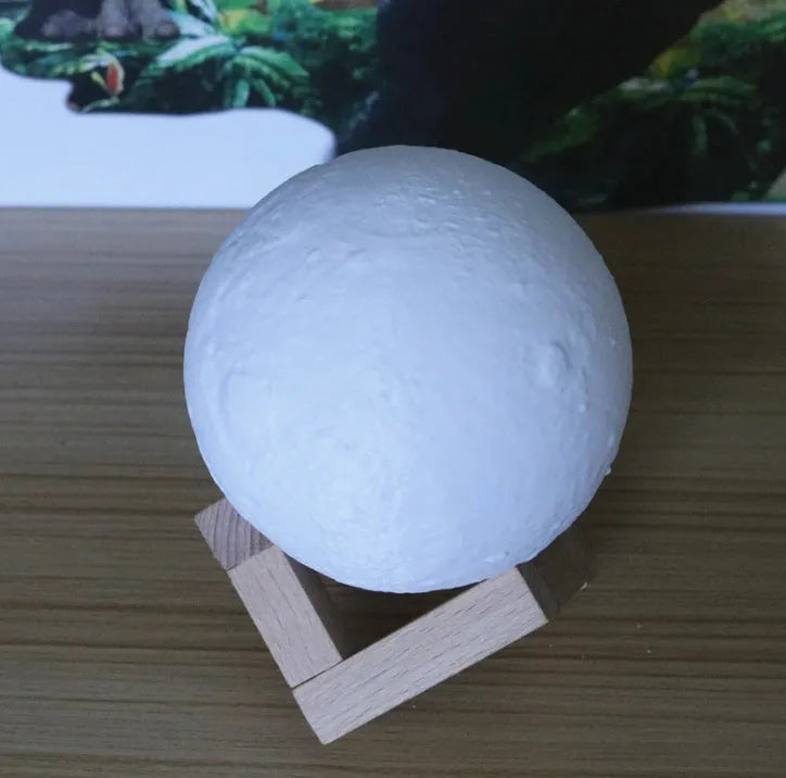 Luna Tranquil Moon Lamp with realistic moon texture and touch colour control on a bedside table