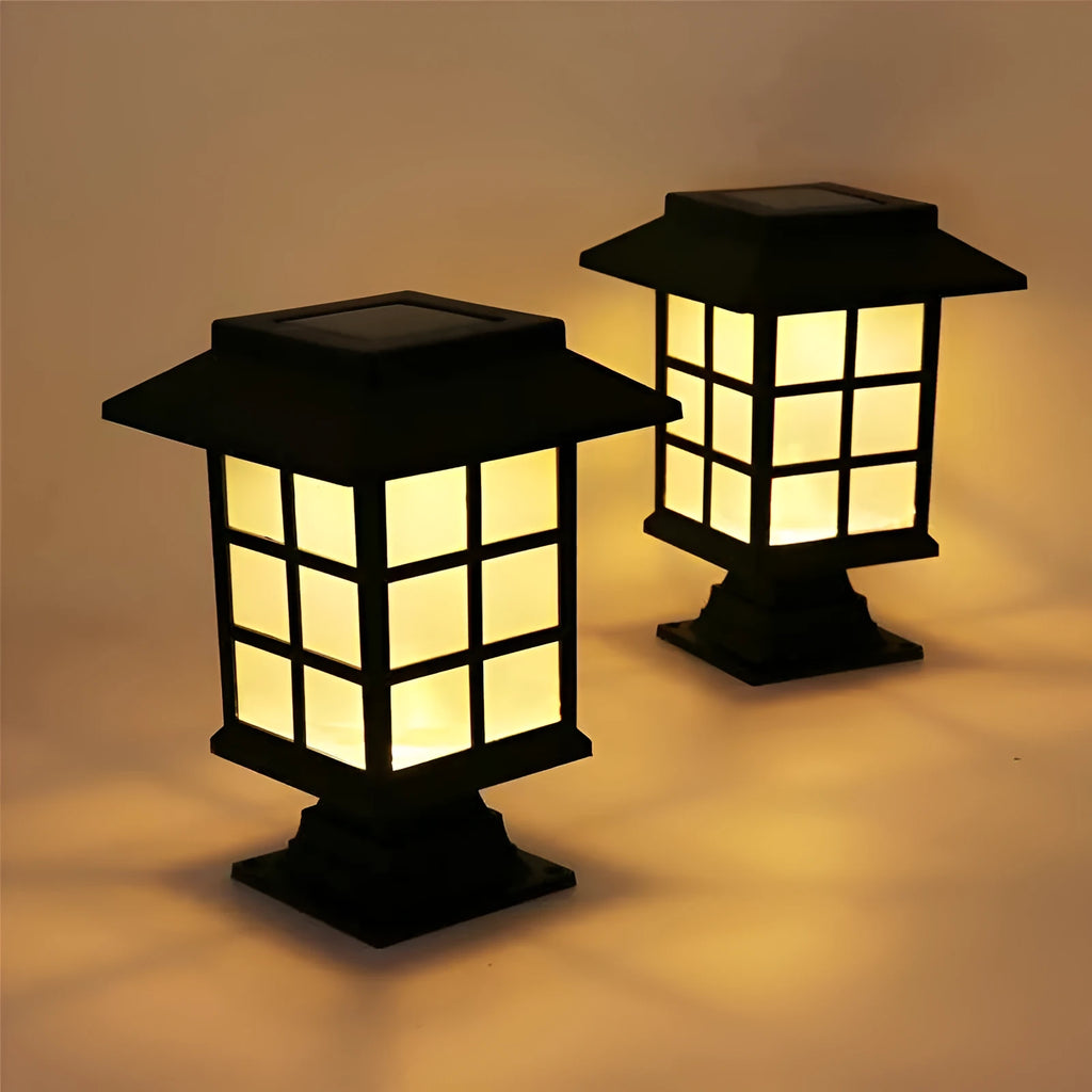 Black solar outdoor LED lawn light with decorative windows, IP65 waterproof, placed in a garden