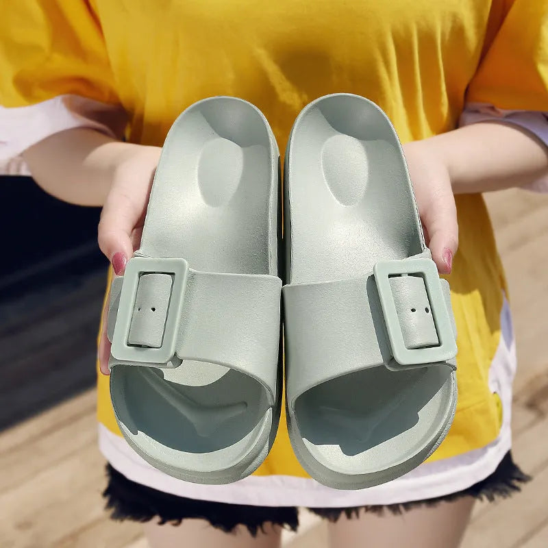 Women's grey blue buckle strap slippers with a soft EVA sole on a light background.