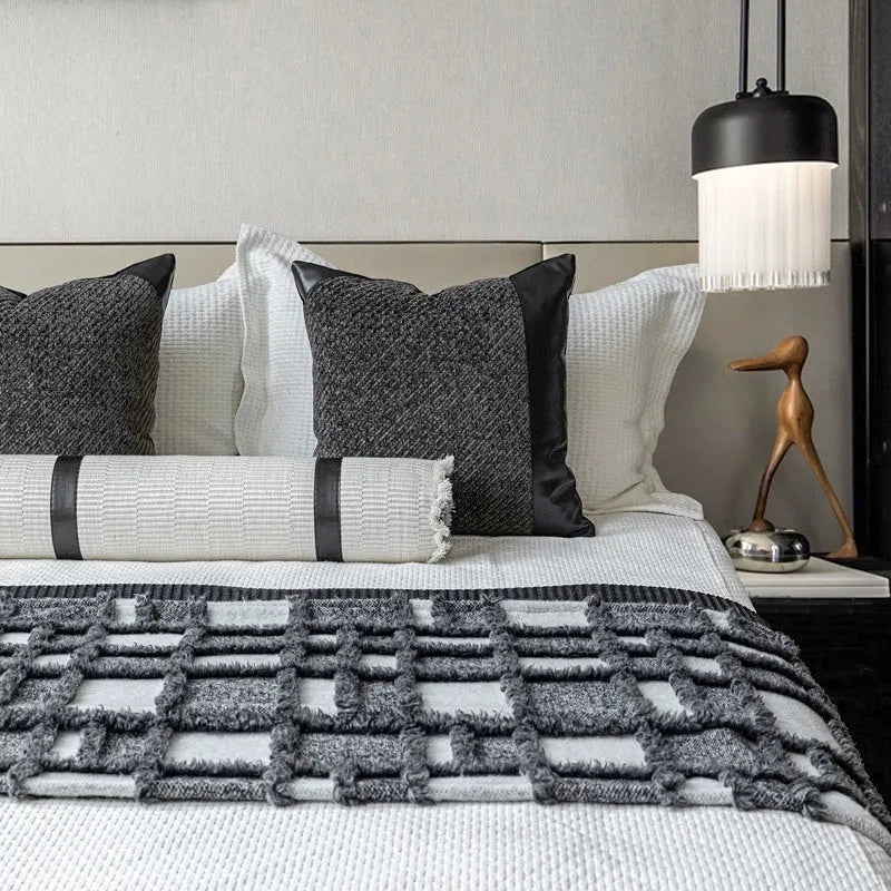 Grey and white plaid bed runner blanket with leather round pillow on bed