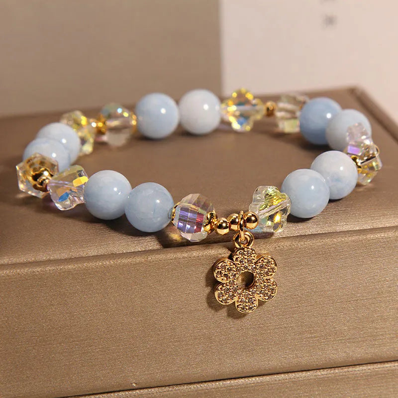 Women's aquamarine crystal bracelet with four-leaf clover design and pearl accents on a wrist.