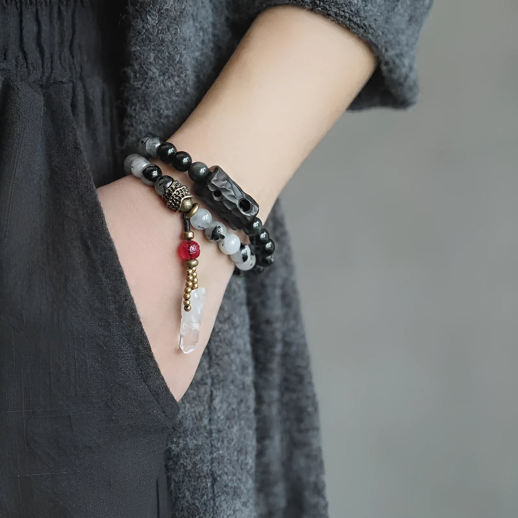 Black hair crystal bracelet with white crystal tassel and bending and lacing design on neutral background