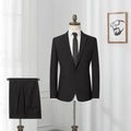 Men's black slim-fit one-button business suit with flat collar and rear slit on a hanger.