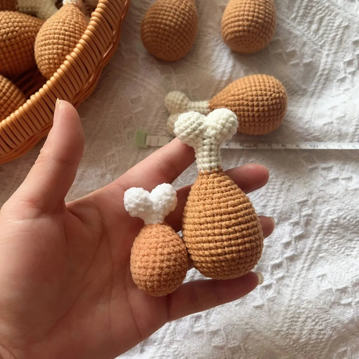 Crocheted chicken leg pendant key chain made of soft plush material, about 8 cm long, on a plain background
