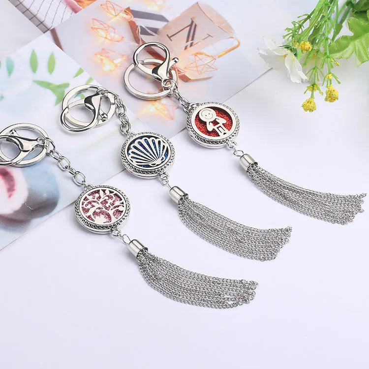 Silver alloy tassel aromatherapy car pendant with long chain on a coloured background.