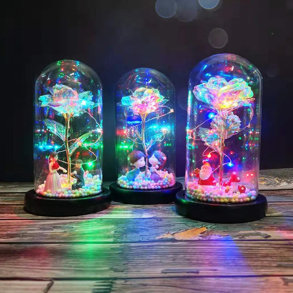 Gold artificial rose inside glass dome with LED lights on black base for home display