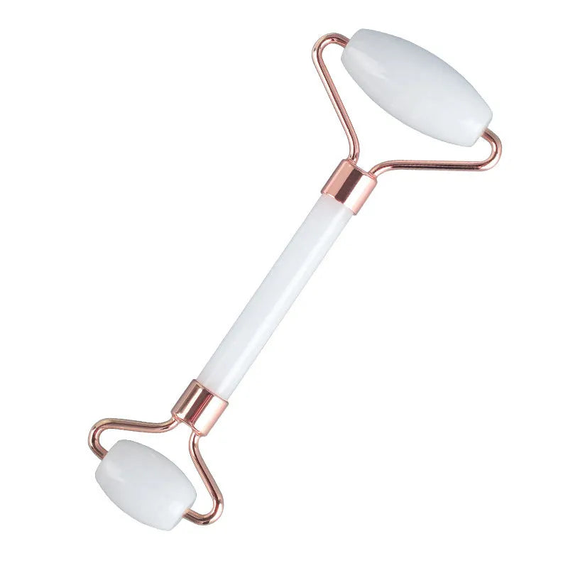 White jade facial roller and gua sha board set on a neutral background.