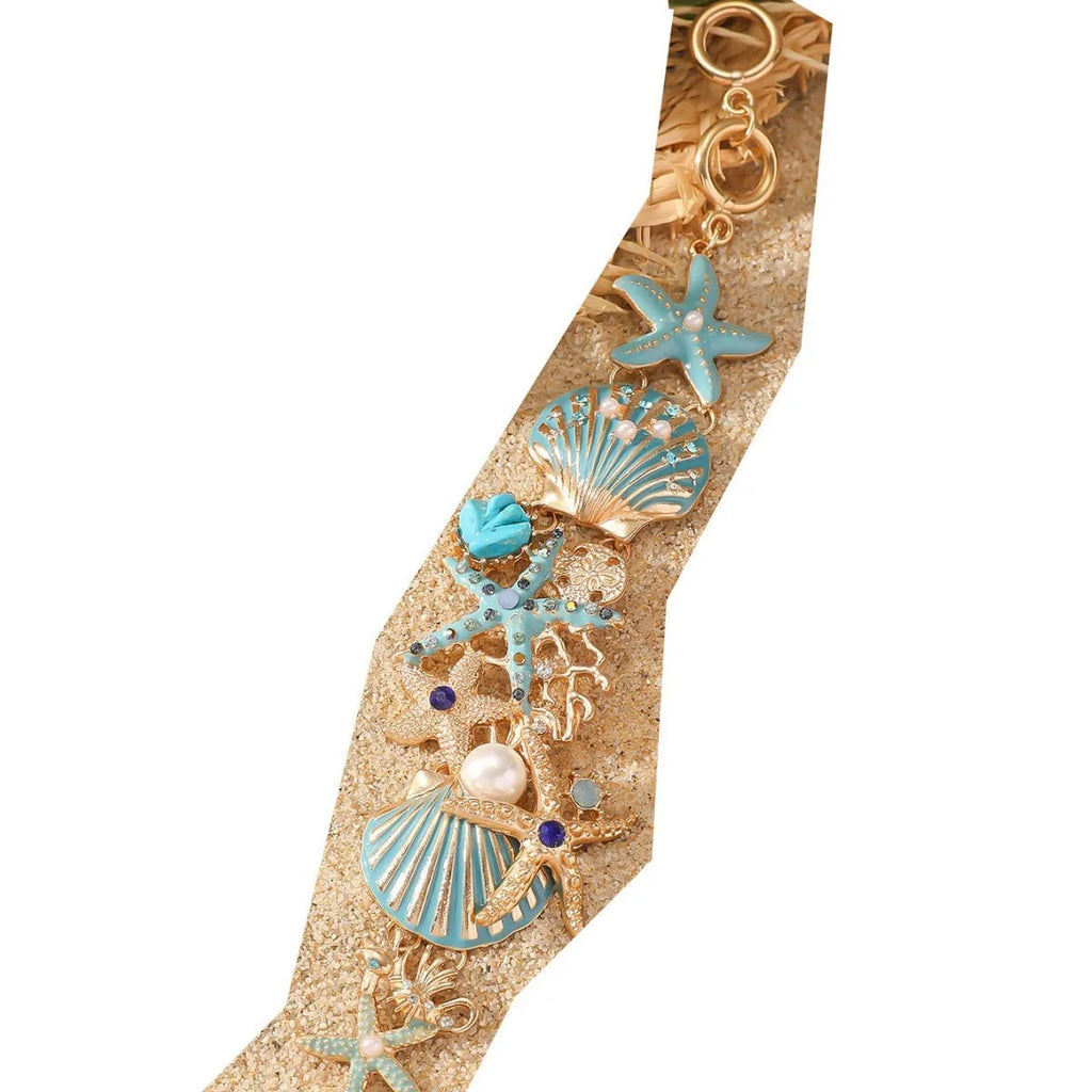 Alloy starfish bracelet with blue coral rhinestone boat anchor charm on a wrist.